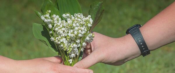 Deux mains qui tiennent un bouquet de muguet