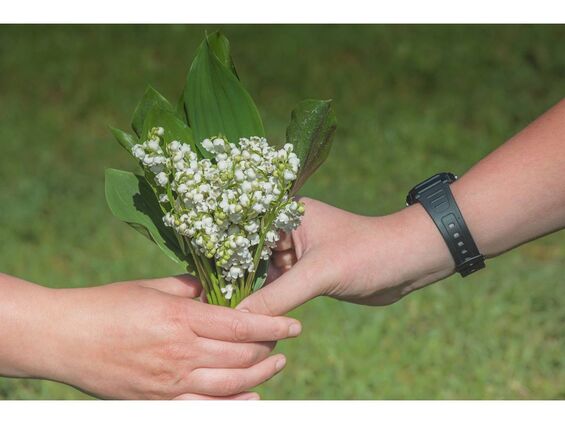 Deux mains qui tiennent un bouquet de muguet
